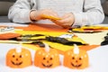 A child creates a pumpkin out of paper. Origami for Halloween, preparation