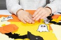 A child creates a pumpkin out of paper. Origami for Halloween, preparation