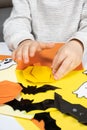 A child creates a pumpkin out of paper. Origami for Halloween, preparation