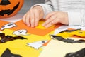 A child creates a pumpkin out of paper. Origami for Halloween, preparation