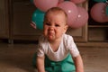 The child cries, gets angry, a little girl, a child, sits on the floor and cries, wrinkled her nose, near the balloons, a holiday. Royalty Free Stock Photo