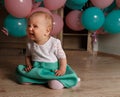 The child cries, gets angry, a little girl, a child, sits on the floor and cries, wrinkled her nose, near the balloons, a holiday. Royalty Free Stock Photo