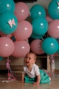 The child cries, gets angry, a little girl, a child, sits on the floor and cries, wrinkled her nose, near the balloons, a holiday. Royalty Free Stock Photo