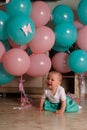 The child cries, gets angry, a little girl, a child, sits on the floor and cries, wrinkled her nose, near the balloons, a holiday. Royalty Free Stock Photo
