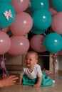 The child cries, gets angry, a little girl, a child, sits on the floor and cries, wrinkled her nose, near the balloons, a holiday. Royalty Free Stock Photo