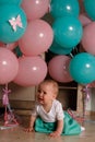 The child cries, gets angry, a little girl, a child, sits on the floor and cries, wrinkled her nose, near the balloons, a holiday. Royalty Free Stock Photo