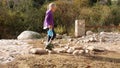 A child crosses a stream over stones without wetting his feet