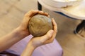 A child crushes a large piece of clay for modeling with his hands