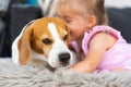 Child cuddle a dog on backyard sofa.