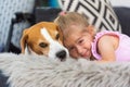 Child cuddle a dog on backyard sofa.