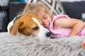 Child cuddle a dog on backyard sofa.