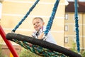 Child, cute caucasian boy riding swing on playground near in a town Royalty Free Stock Photo