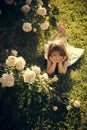 Child with cute smile at blossoming rose flowers