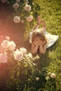 Child with cute smile at blossoming rose flowers. Growth and flourishing. Innocence, purity and youth concept Royalty Free Stock Photo