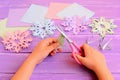 Child cuts snowflakes from a paper. Child holds scissors and folded paper sheet in hands. Exciting childhood winter activity