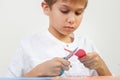 Child cutting red paper heart with scissors