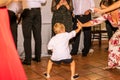 Child dancing with several adults in the celebration of a wedding, encouraging people.