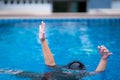 Child in danger drowning in the pool, kid girl cannot swim to deep water and raise two hand for help on swimming pool