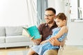 child daughter family happy reading book education literature father sofa playing fun together girl cheerful smiling Royalty Free Stock Photo