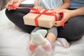 Child daughter unwrapping gift box with her mom