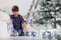 Child decorate the christmas tree with balls and ladder at home