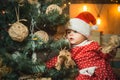 Child decorate the Christmas tree on wooden background. Happy children. Christmas Babies. Cute little child is Royalty Free Stock Photo