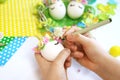 Child decorates an egg for Easter, makes a unicorn from an egg on a white table.