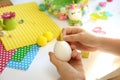 Child decorates an egg for Easter, makes a unicorn from an egg on a white table.