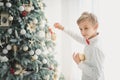 Child decorating Christmas tree at home. Boy hangs Christmas balls on tree. Christmas Eve concept Royalty Free Stock Photo