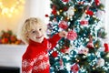 Child decorating Christmas tree at home. Little boy in knitted sweater with Xmas ornament. Family with kids celebrate winter Royalty Free Stock Photo