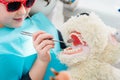 Child at dentist office looking after teeth of pet toy