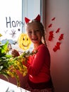 Child painting pumpkin on window preparing celebrate Halloween. Little kid draws decorates room interior with paper bats