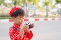 Child with digital compact camera outdoors. Cute little Vietnamese boy in ao dai dress smiling. Tet holiday Royalty Free Stock Photo