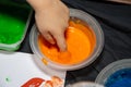 a child dipping his finger into a pot of orange paint for finger painting Royalty Free Stock Photo