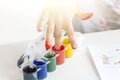 Child dips his fingers into jars of paint, gouache. Palms painted on childrens hands with multi-colored paints. Childs hobby Royalty Free Stock Photo