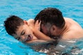 child with disability laughs and plays in his father& x27;s arms in a swimming pool Royalty Free Stock Photo