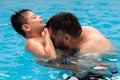 child with disability laughs and plays in his father& x27;s arms in a swimming pool Royalty Free Stock Photo