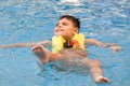 disabled child smile and swim in pool with orange vest float