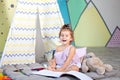 Child does homework child draws in kindergarten. a preschooler learns to write and read. Creative kid. Little smiling girl draws w