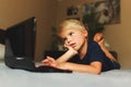 Child does homework , lying in bed using his laptop or skyping. Royalty Free Stock Photo