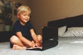 Child does homework , lying in bed using his laptop or skyping. Royalty Free Stock Photo