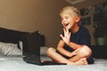Child does homework , lying in bed using his laptop or skyping. Royalty Free Stock Photo