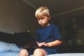 Child does homework , lying in bed using his laptop or skyping. Royalty Free Stock Photo