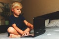 Child does homework , lying in bed using his laptop or skyping. Royalty Free Stock Photo