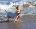 Child, dog and beach with kid playing with pet animal running on sand by the ocean. Holiday, children and dogs swimming Royalty Free Stock Photo