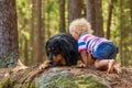 Child and dog, blond little boy cuddles with a black blonde hovie on a rock Royalty Free Stock Photo