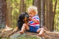 Child and dog, blond little boy feeds a black blonde Hovie on a rock Royalty Free Stock Photo