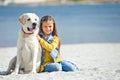 Child with a dog in nature. Little girl with a labrador retriever by the sea.