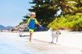 Child and dog playing on tropical beach Royalty Free Stock Photo