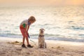 Child and dog playing on tropical beach Royalty Free Stock Photo